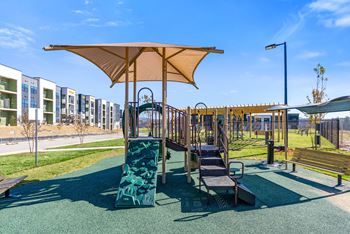 A playground with a green slide and a brown canopy.